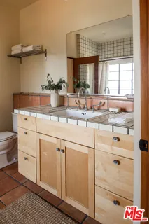 a bedroom with a bed a table and three windows