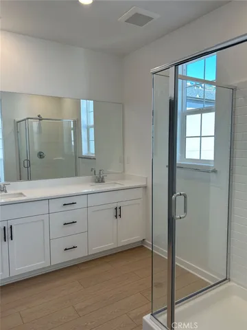 a spacious bathroom with double vanity a sink a mirror and a shower