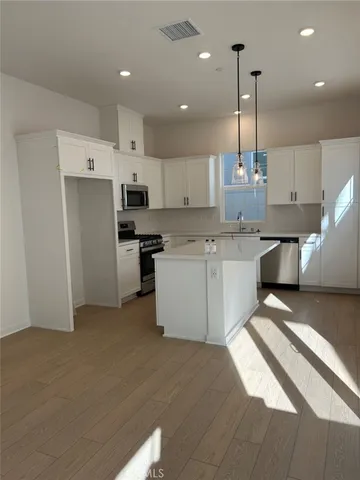 a kitchen with stainless steel appliances granite countertop a sink a stove a refrigerator and island with wooden floor