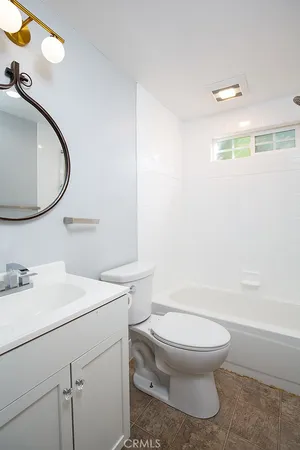 a bathroom with a toilet sink vanity tub and mirror