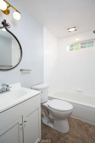 a bathroom with a toilet sink vanity tub and mirror