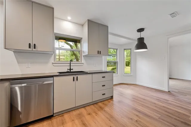 a kitchen with granite countertop white cabinets white appliances and a wide window