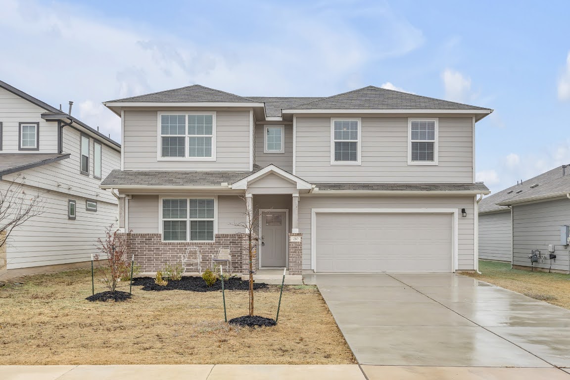Traditional-style house featuring brick siding, concrete driveway, a garage, and roof with shingles