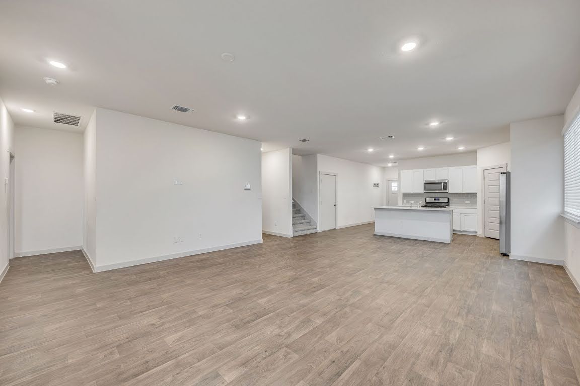 210 Big Cypress Bayou Road Hutto, TX 78634 - Photo 10 of 27 Unfurnished living room featuring recessed lighting, light wood finished floors, and stairs