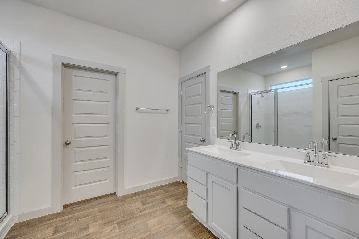 210 Big Cypress Bayou Road Hutto, TX 78634 - Photo 13 of 27 Full bathroom featuring a stall shower, light wood-type flooring, and double vanity