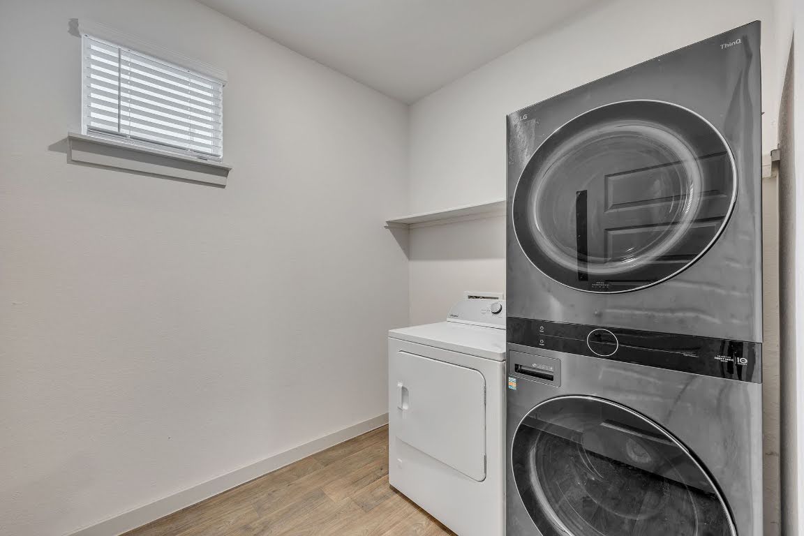 210 Big Cypress Bayou Road Hutto, TX 78634 - Photo 18 of 27 Laundry room featuring light wood-style floors and stacked washing machine and dryer