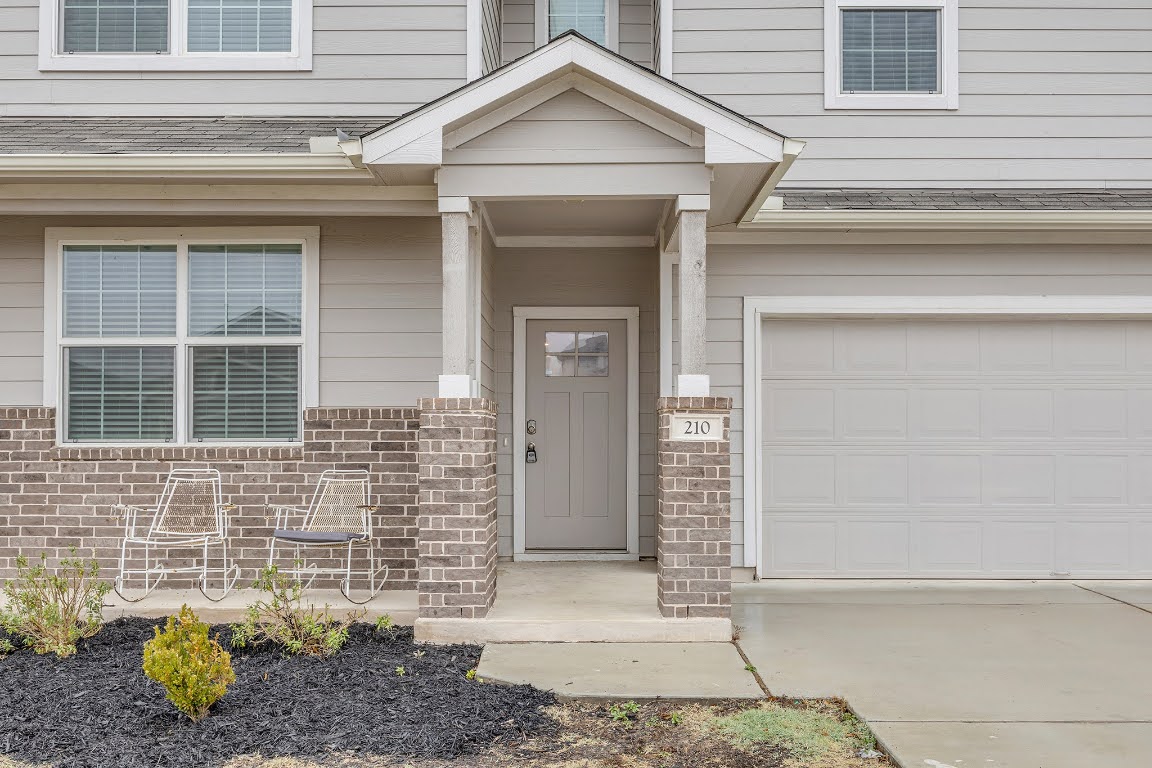 210 Big Cypress Bayou Road Hutto, TX 78634 - Photo 3 of 27 Property entrance with a shingled roof, brick siding, concrete driveway, and a garage