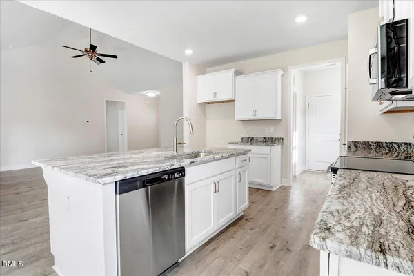 a kitchen that has a lot of white cabinets and wooden floor