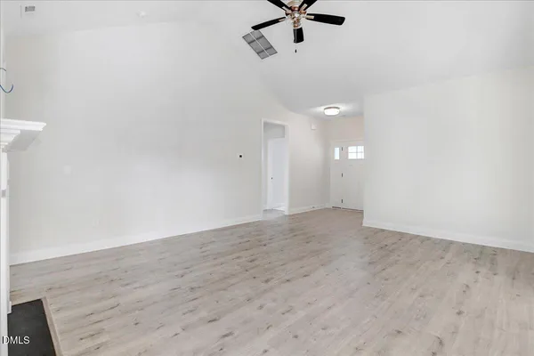 a view of an empty room with wooden floor fireplace and a window