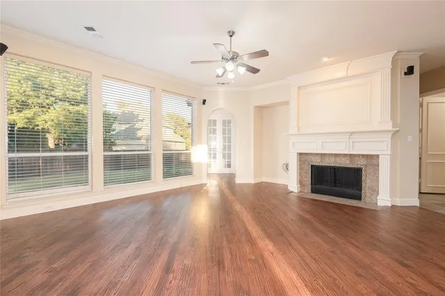 a view of an empty room with wooden floor fireplace and a window