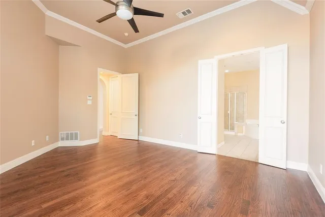 an empty room with wooden floor fan and windows