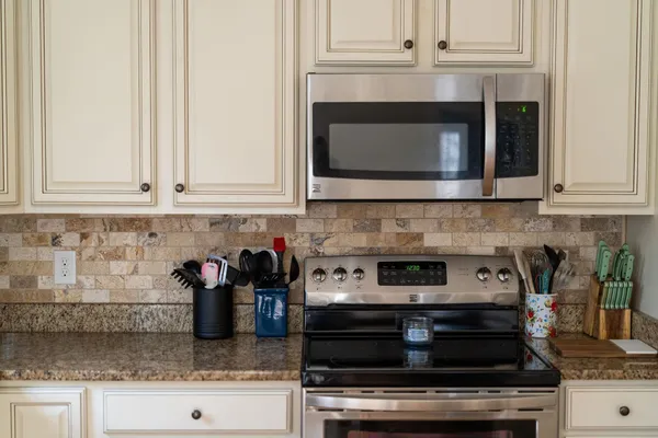 a kitchen with granite countertop white cabinets and stainless steel appliances
