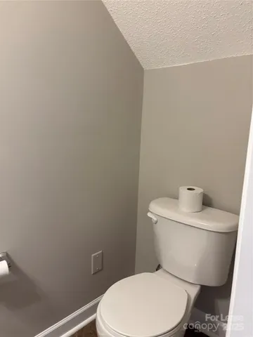 a white toilet sitting next to a white wall