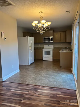 a kitchen with stainless steel appliances granite countertop a sink a stove top oven a refrigerator and a dishwasher