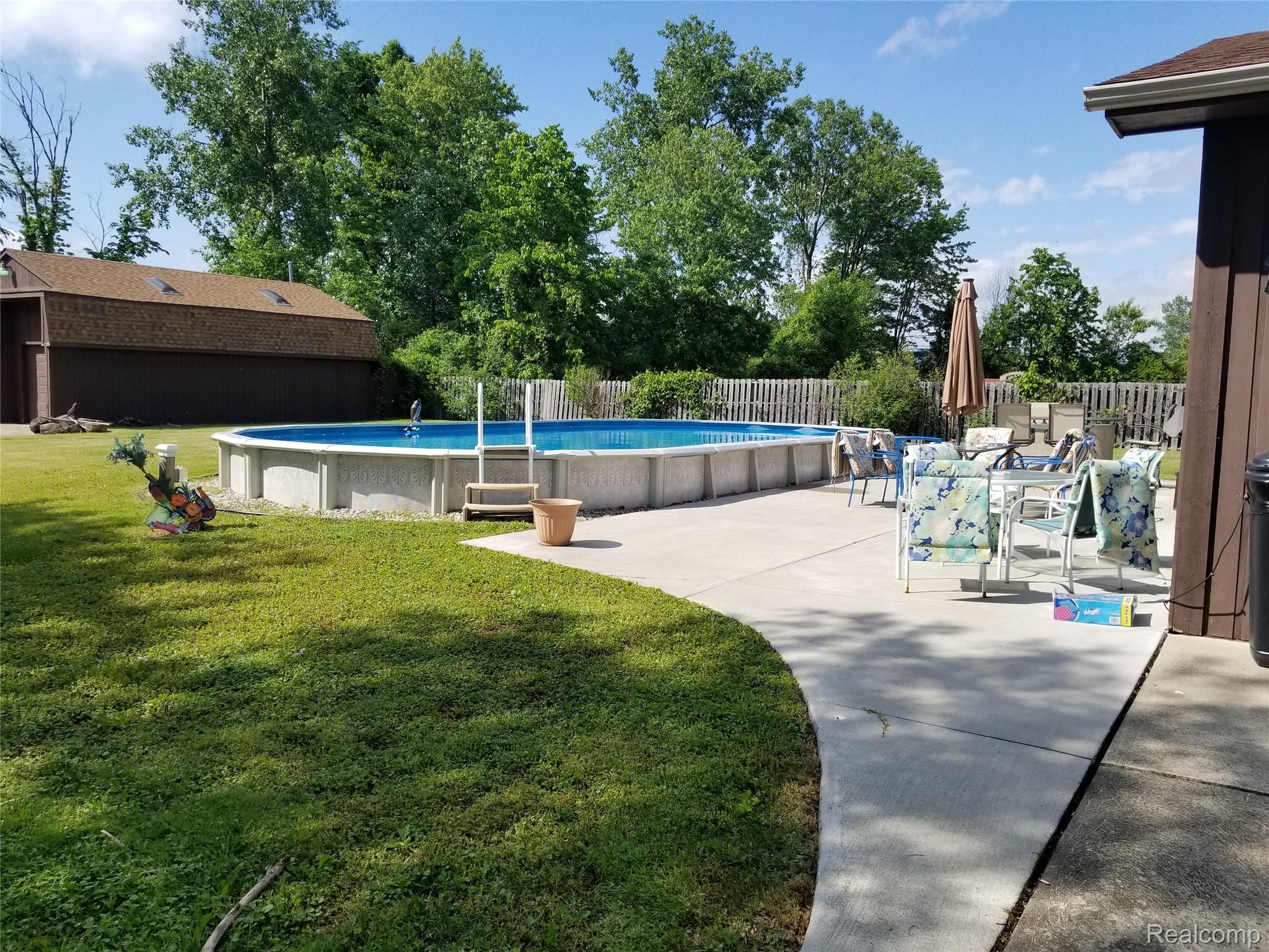 34781 Union Lake Road Clinton Township, MI 48035 - Photo 24 of 38 Expansive yard featuring a large above-ground pool, concrete patio, and separate shed structure