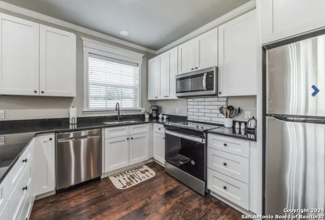 a kitchen with granite countertop white cabinets and stainless steel appliances