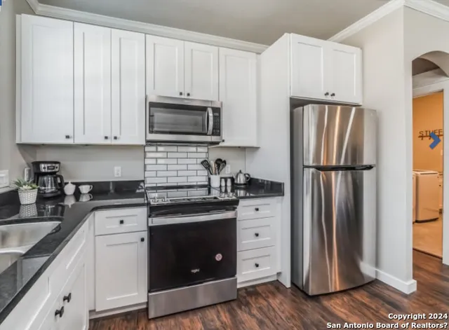 a kitchen with granite countertop a refrigerator stove and sink