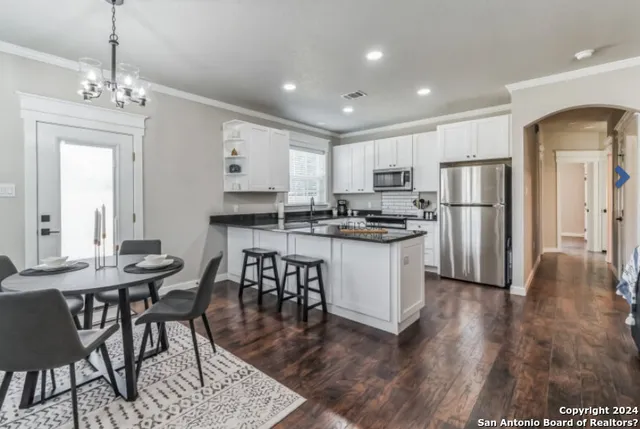 a kitchen with stainless steel appliances kitchen island granite countertop a dining table chairs refrigerator and sink