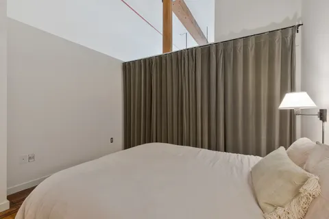 a bedroom with a bed and a lamp on the dresser