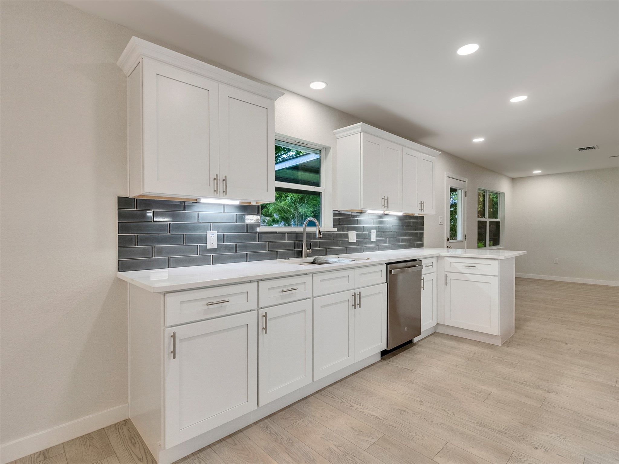 10315 Winding Trail Road La Porte, TX 77571 - Photo 8 of 24 Discover the heart of this home in a sleek kitchen featuring elegant white cabinetry, modern stainless steel appliances, and stylish subway tile backsplash, all basking in natural light through generous windows.