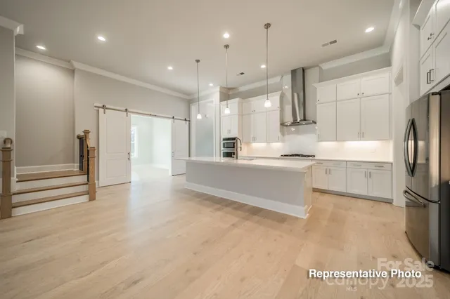 a large white kitchen with a refrigerator a sink and a stove top oven