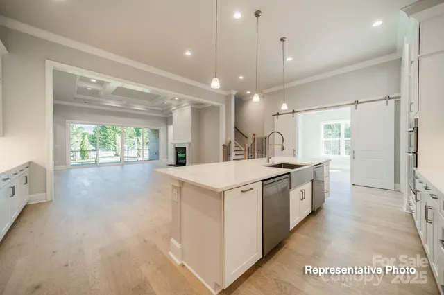 a large white kitchen with a large window a sink and stainless steel appliances