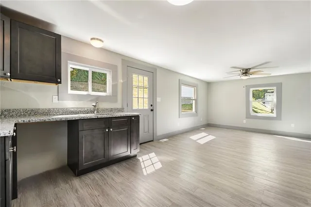 a kitchen with granite countertop a stove a sink and a granite counter tops with wooden floors