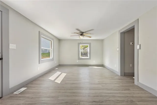 a view of empty room with wooden floor and fan