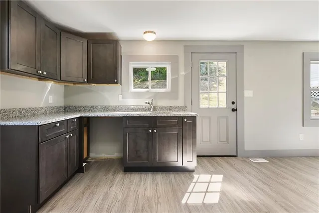 a kitchen with granite countertop a sink a window and cabinets