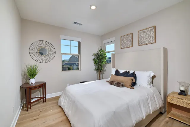 a bedroom with a bed and a potted plant on dresser