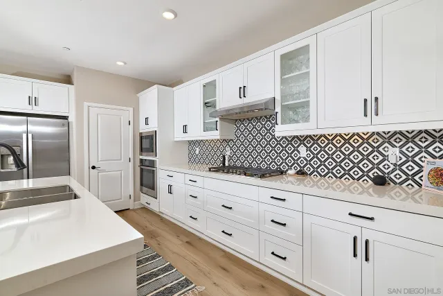 a kitchen with granite countertop white cabinets and stainless steel appliances