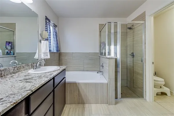a bathroom with a granite countertop sink and mirror with bathtub