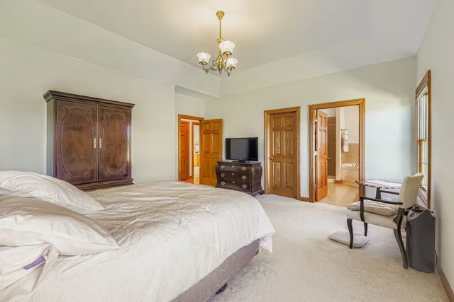 a spacious bedroom with a large bed and a chandelier