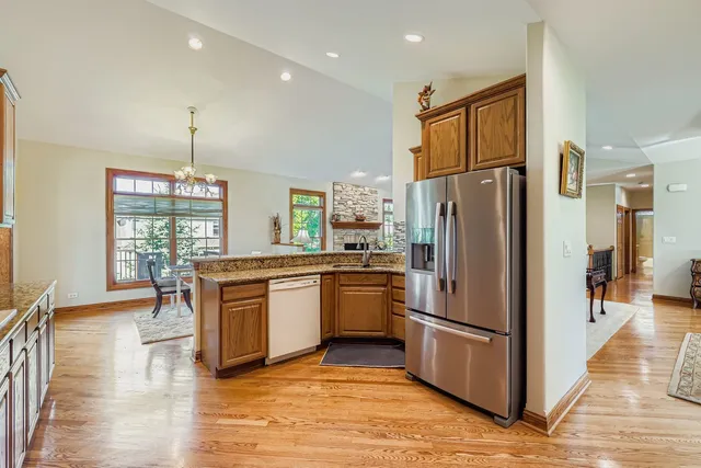 a kitchen with stainless steel appliances granite countertop a refrigerator a stove and a wooden floors