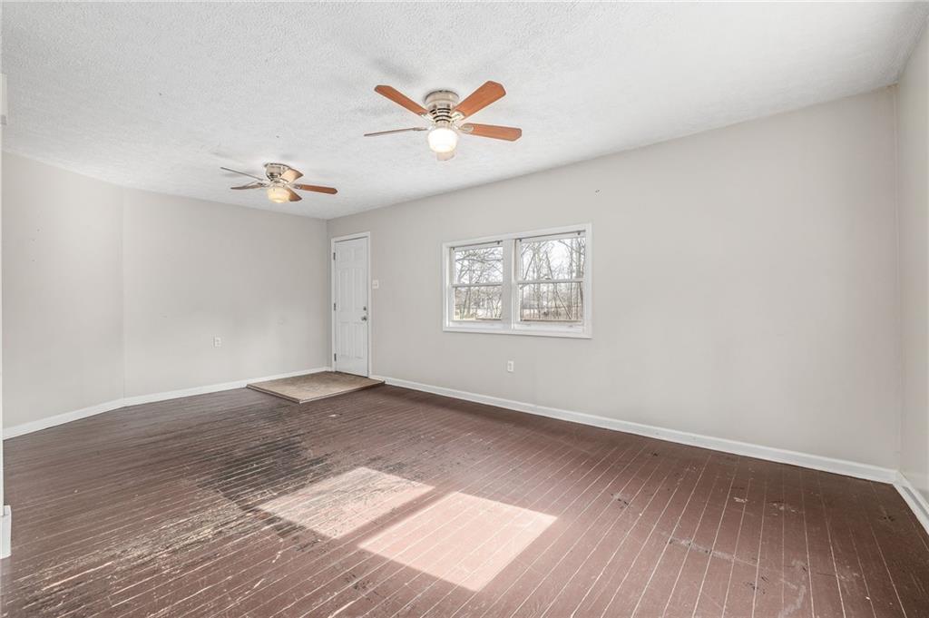 75 Lake Street Jefferson, GA 30549 - Photo 6 of 35 an empty room with wooden floor chandelier fan and windows