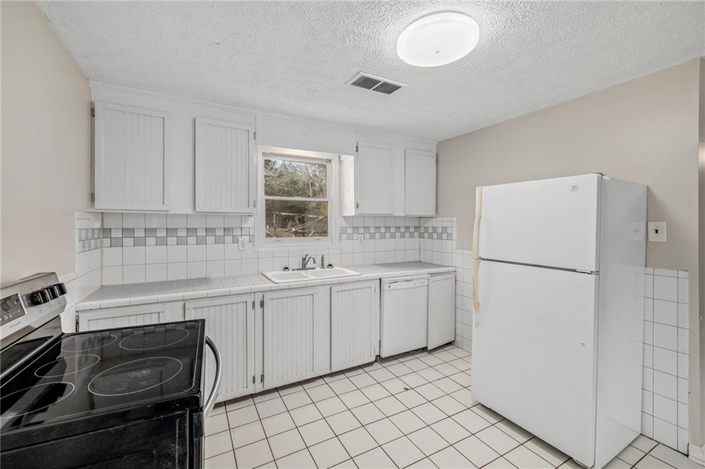 75 Lake Street Jefferson, GA 30549 - Photo 9 of 35 a kitchen with white cabinets and white appliances