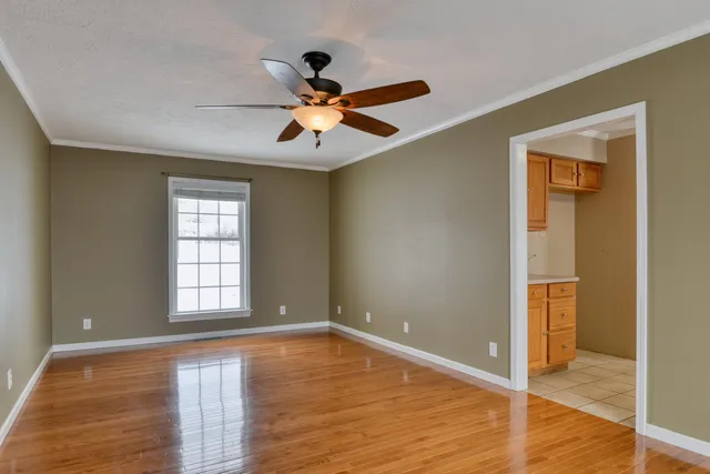 a view of an empty room with a window and wooden floor