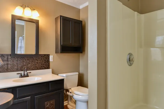 a view of a hallway with wooden floor and a bathroom