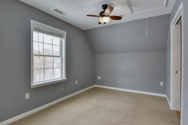 an empty room with windows and fan