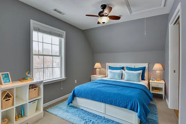 a bedroom with a bed a ceiling fan and a dresser