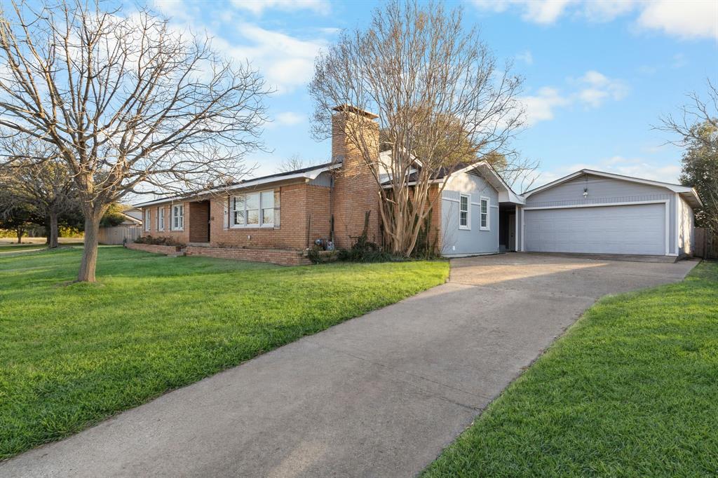 2208 Lake Ridge Circle Waco, TX 76710 - Photo 9 of 40 Single story home featuring a chimney, concrete driveway, brick siding, a front lawn, and an outdoor structure