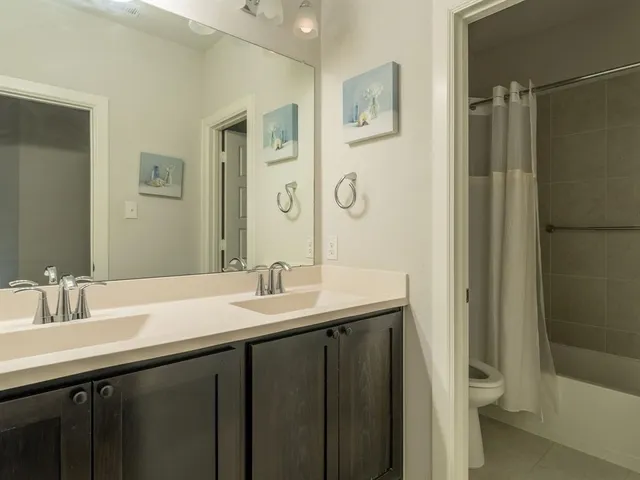 a bathroom with a granite countertop sink a toilet a mirror and shower