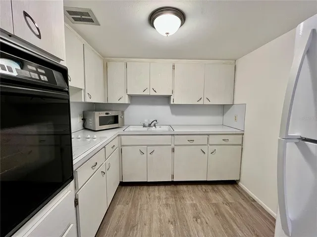 a kitchen with granite countertop white cabinets and stainless steel appliances