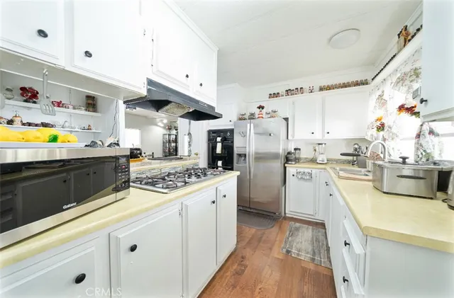 a kitchen with stainless steel appliances granite countertop a lot of counter space and wooden floors