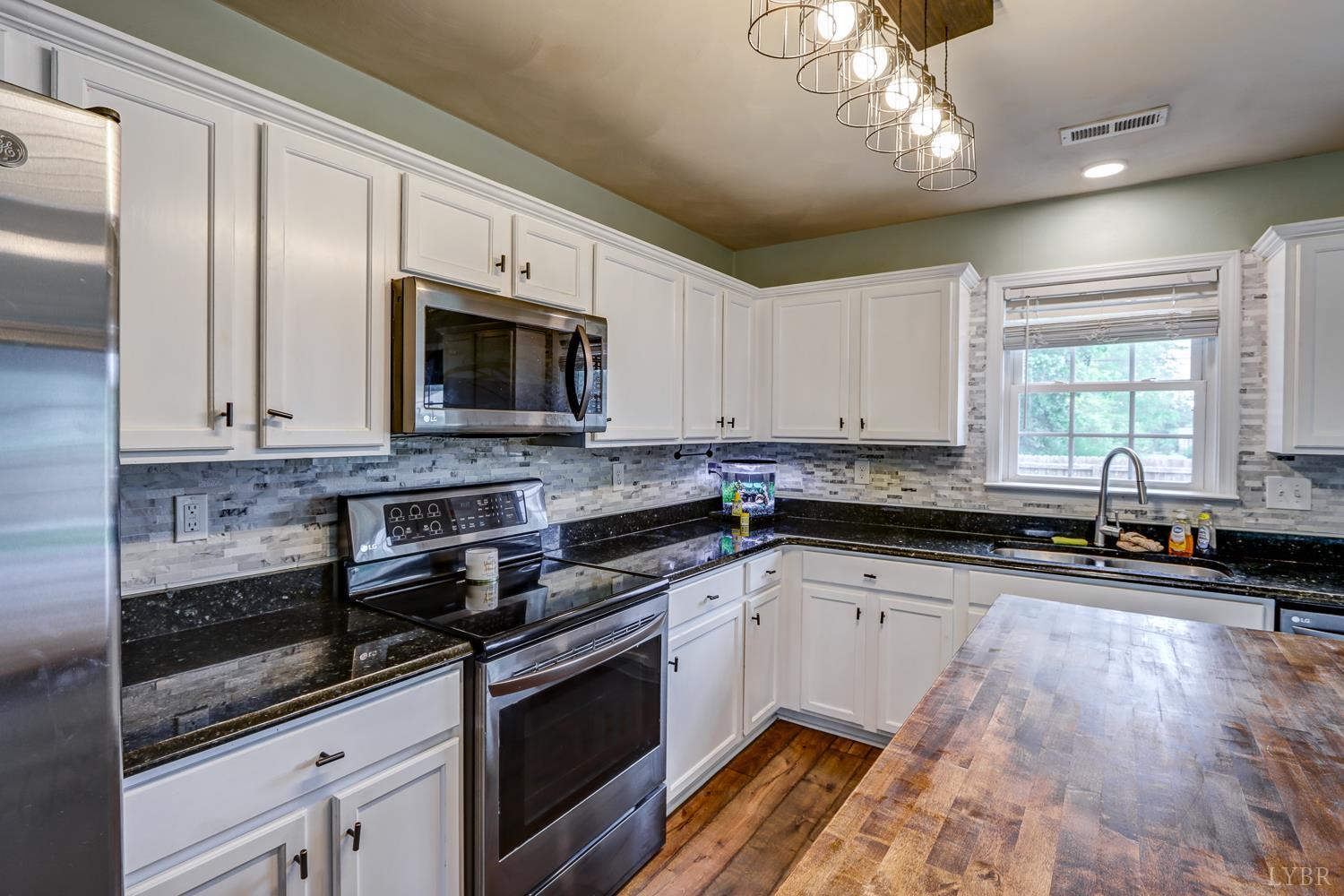 1057 Old Trail Road Forest, VA 24551 - Photo 16 of 49 a large kitchen with granite countertop a stove a sink dishwasher and a microwave oven with white cabinets