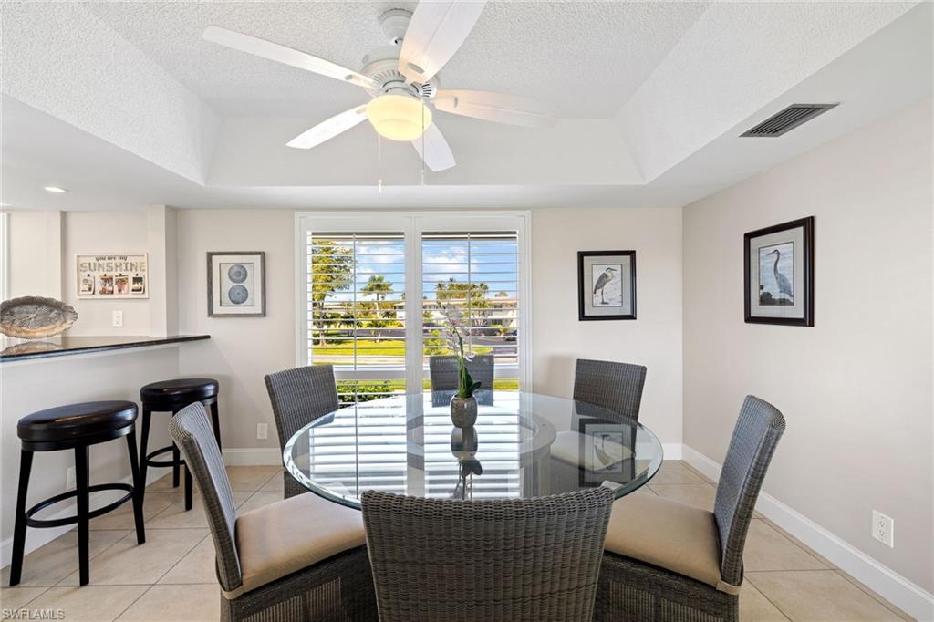 108 Penny Lane, Unit 4 Naples, FL 34112 - Photo 8 of 31 a dining room with furniture a rug and a chandelier