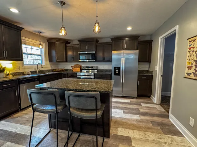 a kitchen with kitchen island a counter space a sink appliances and cabinets