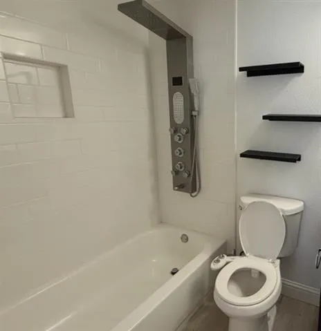 a white toilet sitting next to a bath tub