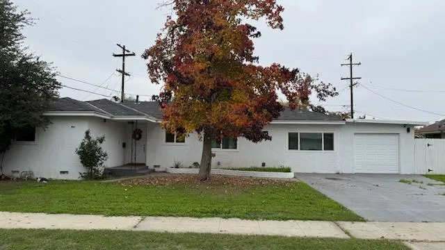 a view of a white house with a yard and a large tree