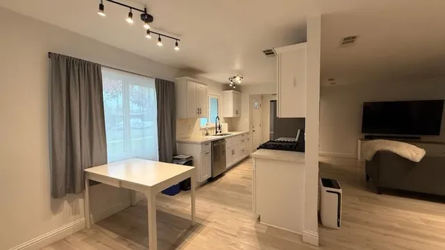 a kitchen with stainless steel appliances kitchen island granite countertop a table chairs in it and a refrigerator